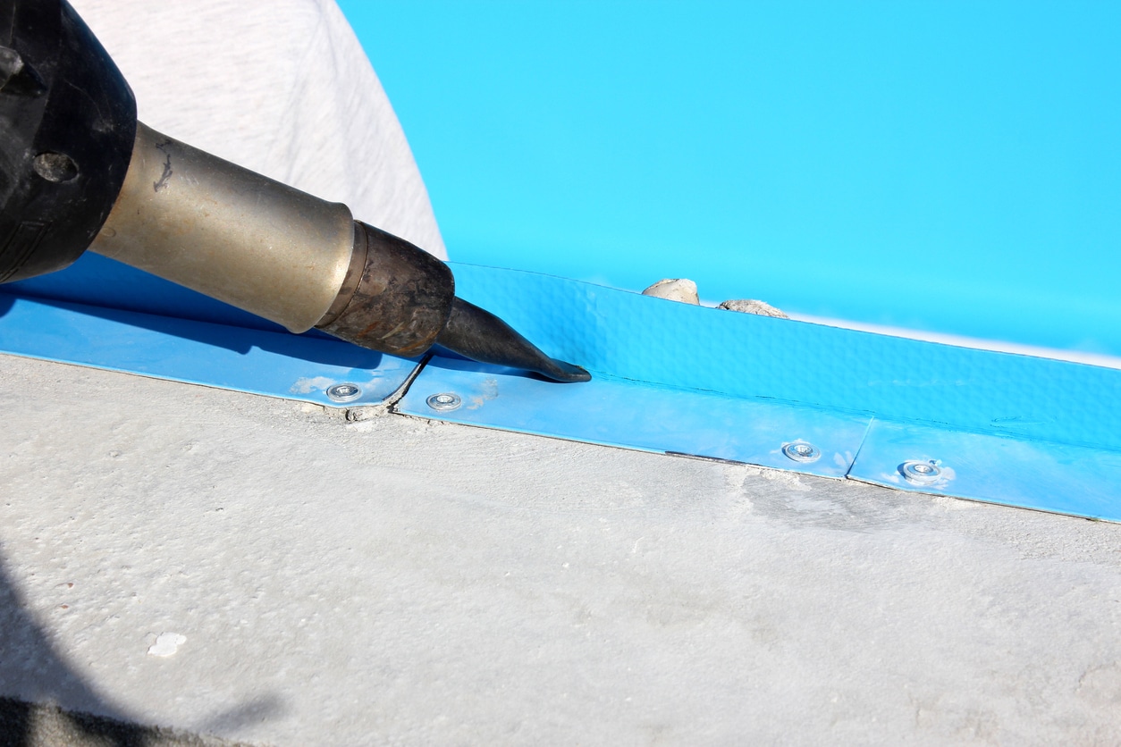 A worker welds plastic cover for water pool. Water pool cover replacement.